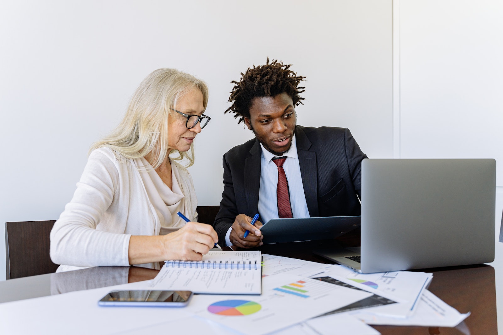 Elderly Woman Looking at the Computer Beside a Man in Black Suit