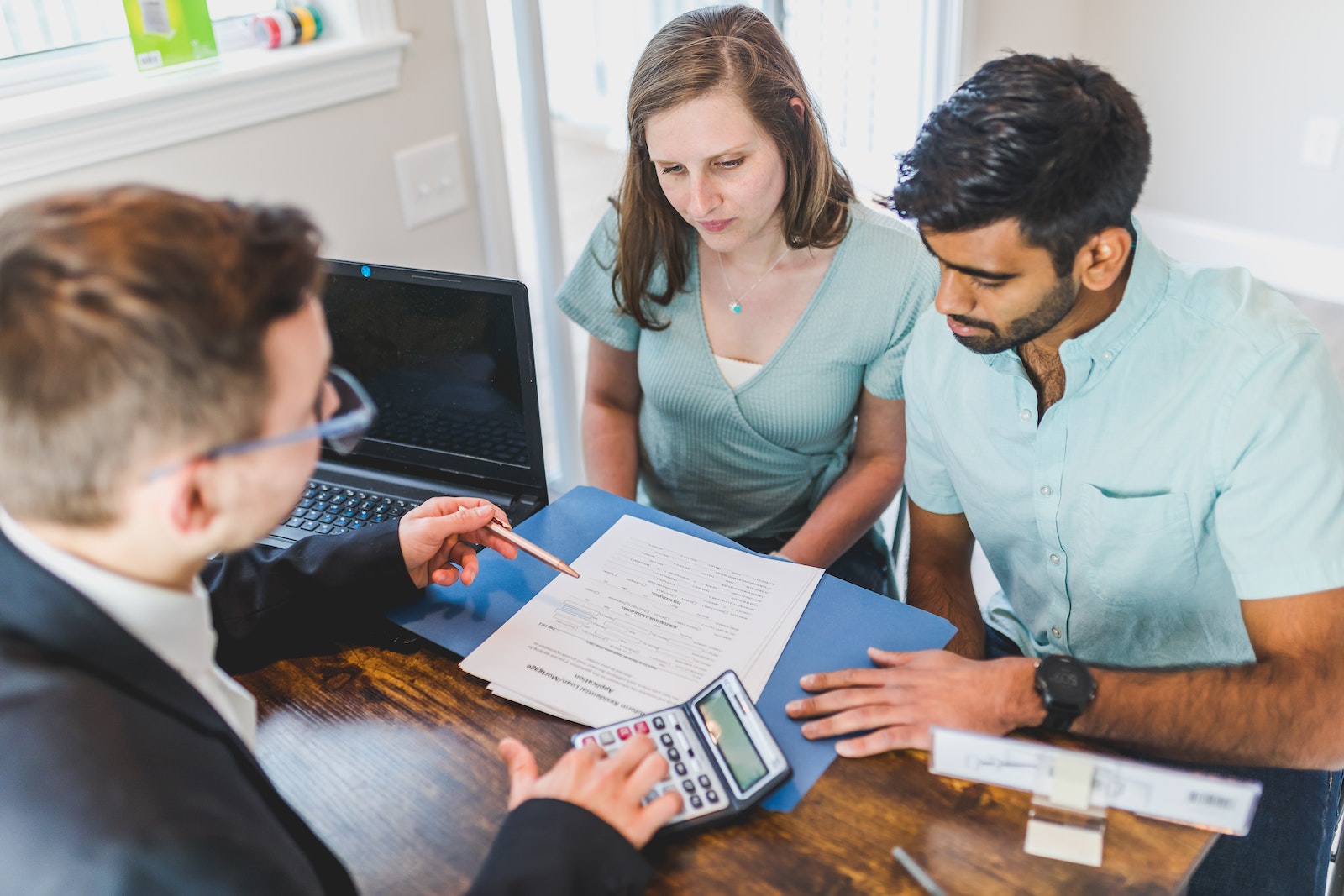 Real Estate Agent in Black Coat Discussing an Ownership Agreement to a Couple Inside the Office